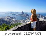 Tourism in Rio de Janeiro. Back view of traveler girl enjoying sight of famous Guanabara Bay with Sugarloaf Mountain in Rio de Janeiro, UNESCO World Heritage, Brazil.