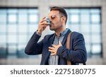 Small photo of Stress and asthma. Young businessman treating asthma attack with inhaler. Health care concept