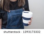 Young woman holding a silicone collapsible cup, reusable coffee tumbler.