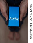 Small photo of December 3, 2022 Almaty Kazakhstan: Barefoot woman holding smartphone with zappos logo.