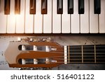 Small photo of Piano and tuning peg guitar with shine and sheet music background. Horizontal Composition.Top view