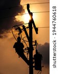 Small photo of The silhouette of power lineman climbing on an electric pole with a transformer installed. And replacing the damaged hotline clamp, bail clamp, dropout and surge arrester that causes a power outage.