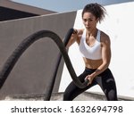 Concept image - Powerful fitness woman training with black battle ropes crossfit at outdoor, with white top