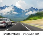 Car drives fast on the highway against the backdrop of a mountain range.