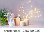 Small photo of praying angel, candles, flowers and books on table, abstract light background. Christmas or Easter holiday concept. Religious church holiday. symbol of faith in God, Christianity Feast
