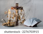 Crucifixion cross, candle and biblical book close up on table. Easter, Orthodox palm Sunday. Good Friday. symbol of Christianity, faith, Lent, prayer. Church religious holiday.