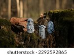 Small photo of vintage ritual stone idols on tree stump close up, abstract natural forest background. old gods totems in traditional Slavic folk style. folklore Ethnic handicraft. Attribute of pagan religious rites.