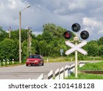 Car in front of a railway crossing. Red traffic light at the railway crossing.