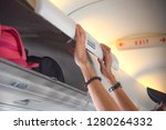 hand of woman passenger of the aircraft holding cover of overhead locker to keep in closed condition, to keep luggages in saft during the flight