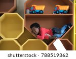 Small photo of a naughty preschool boy playing around in the slot pigeonhole box in classroom