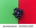 Cluster of moon drops dark purple grapes on duotone red green background. Wine production harvest vitamins healthy lifestyle concept. Creative food poster with copy space