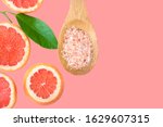 Ayurveda face skin scrub ingredients Himalayan salt in wooden spoon sliced grapefruit green leaf on cherry pink background. Beauty face care natural organic cosmetics concept