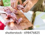 Small photo of Man's hands cutting and disjointing raw rabbit meat. Preparing ingredients for cooking paella jambalaya, barbecue. Outdoor picnic, weekend, summer. Lifestyle.