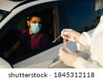 Doctor doing a PCR test COVID-19 on a patient through the car window. PCR diagnostic for Coronavirus presence,doctor in PPE holding test kit