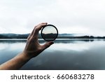 Hand Holding DSLR Camera Lens Filter in Hand in Front of River Mountain Nature Scene