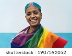 Young activist woman smiling and  holding rainbow flag symbol of Lgbtq social movement