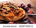 Small photo of Rustic plum cake on wooden background with plums around. Plum pie concept