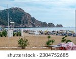 Small photo of Alanya, Turkey - October 23, 2020: View of Damlatas Beach in Alanya. Sculpture of a pegasus among the sand against the backdrop of a seascape, sun loungers with umbrellas and mountains with a castle