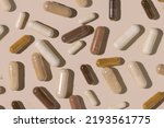 Mix of medical capsules on light beige top view, hard shadows. Preventive medicine and healthcare, taking dietary supplements and vitamins.  Assorted pharmaceutical medicine capsules