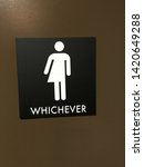 Small photo of Black sign with white icon and lettering denoting a unisex bathroom. Icon is half woman and half man and says "whichever".