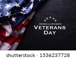Happy Veterans Day. American flags with the text thank you veterans against a blackboard background. November 11.