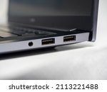 Close-up of a part of a laptop standing on a light background. Large USB ports on the laptop. Open laptop
