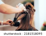 

Woman Having her Hair Straighten with a Brush and a Hair Dryer. Hairdresser drying clients hair working with professional tools
