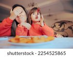 Small photo of Funny Playful Girl Eating Awkwardly Exasperating her Mom Naughty child forgetting about table manners embarrassing her mother