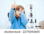 Small photo of Cute Little Girl Covering One Eye During Ophthalmological Consult. Toddler child pointing to a vision chart during eye check