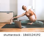 Pregnant woman practicing yoga at home with laptop. Expectant mother doing prenatal video training class indoors. Female exercise, meditate during pregnancy. Online fitness class on digital devices.