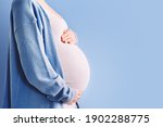 Beautiful pregnant woman hugging her belly in white background. Expectant mother waiting for baby birth during pregnancy. Concept of maternal health, visiting doctor and gynecological checkup.