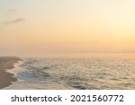 Small photo of Foggy sunrise over the sea. Pastel shades. Beautiful landscape. Sandy beach of the ocean. Sunset sky. Clouds and fog. Coast. A flock of birds flies away like a wedge in the sky.