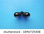 Binoculars on a light blue background. Banner. Flat lay, top view.