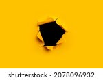 Bright yellow torn paper inside a black hole in a hole