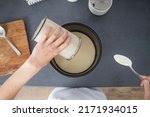 Woman pouring dough from bowl into baking dish. Top view, flat lay.