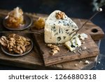 Danish blue cheese on a wooden board with walnut kernels. dark background