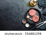 raw burgers - cutlets from organic beef meat with garlic and rosemary in a frying pan on black background, top view with copy space