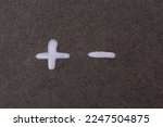 Plus and minus symbols on a gray background. The concept of opposites.