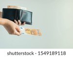 Small photo of Close-up image of a hand holding a leather short wallet with EURO money in it; and another hand bring forward 50 euro banknote to pay for something on white background with copy space.