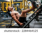 Caucasian man exercising using leg lift stretching equipment and building muscles in gym