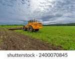 Small photo of Spring photography, landscape with agricultural machinery, a tractor plows the land, plows a field, birds fly over arable land