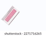 Small photo of A pink piece of chewing gum in an unpacked wrapper on a white background. Flavored chewing gum is used after meals to freshen breath and clean teeth. The habit of chewing gum. Free space for text