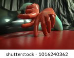 cute short-haired blonde girl posing in latex catsuit and rubber red gloves, alone on a dark background