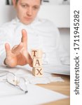 Small photo of Businessman removes wooden blocks with the word Tax. Reduction or restructuring of debt. Bankruptcy announcement. Refusal to pay loans and invalidate them.