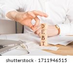 Small photo of Businessman removes wooden blocks with the word Debt. Reduction or restructuring of tax. Bankruptcy announcement. Refusal to pay loans and invalidate them.