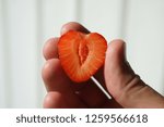 Small photo of A strawberry cut in two looks like a heart lying in the hand.
