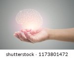 Man holding brain illustration against gray wall background. Concept with mental health protection and care.