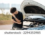 Worried asian young man stands in front of car checking condition after a broken car. Broken car down on the road. emergency service has broken car.