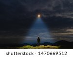 The UFO shines on a male standing on the mountain