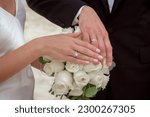 Hands newlyweds with a bouquet. A newly weding couple place their hands on a wedding bouquet